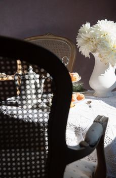 abstract photography over the back of a chair in blur, English style tea break, still life with flowers and donuts in the morning sun, homemade cakes. High quality photo
