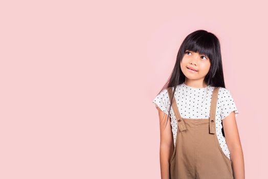 Asian little kid 10 years old looking away to side natural expression at studio shot isolated on pink background, Portrait of Happy child girl smiling staring away thinking