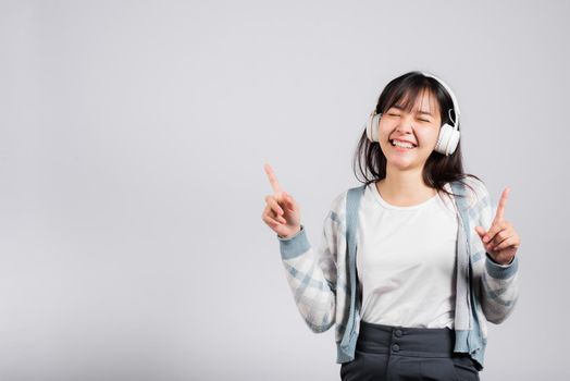 Woman excited smiling listening to music radio in bluetooth headphones and dancing with smartphone studio shot isolated white background, happy Asian young female Karaoke online app in mobile phone