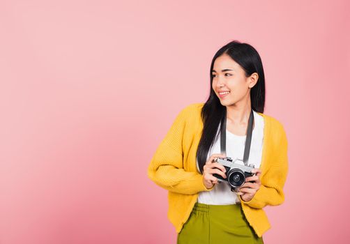 Attractive energetic happy Asian portrait beautiful cute young woman teen excited smiling holding vintage photo camera, studio shot isolated on pink background, traveler female photographer