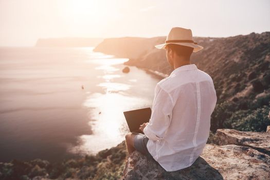 freelancer businessman working remotely on laptop at the beach near the sea