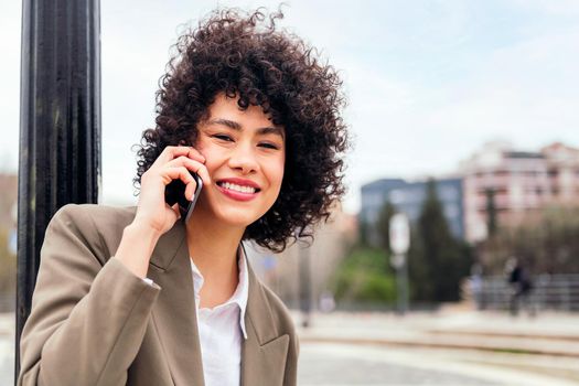 young latin woman smiling happy talking by mobile phone outdoors, concept of communication and urban lifestyle, copy space for text