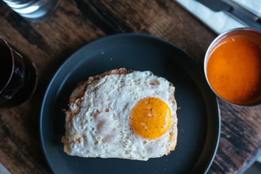 Toast with cheese and sausage covered with fried egg on a plate. Selective focus. Top view.