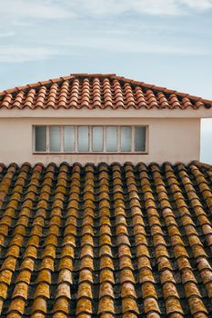 Roof of a house with small window and terracotta tiles