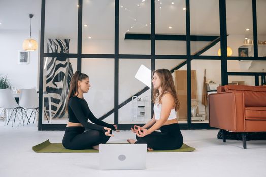 Two young women meditating in lotus pose. Yoga