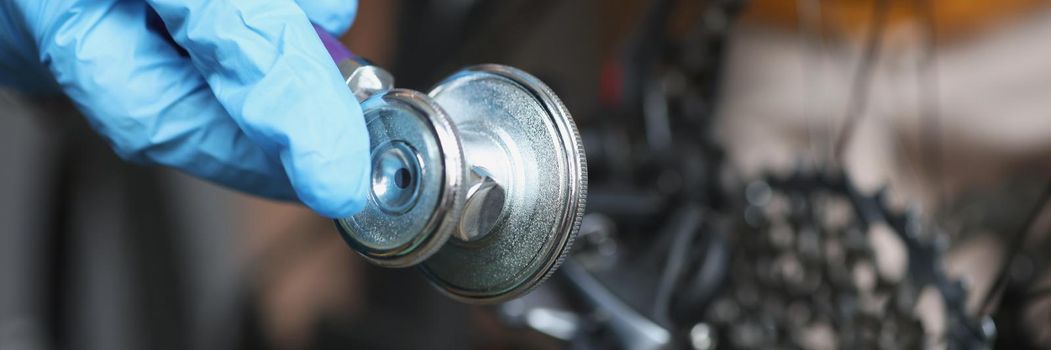 Close-up of person mechanic checkup motorbike vehicle with stethoscope tool. Pit stop for bike to get qualified help. Maintenance service, repair concept