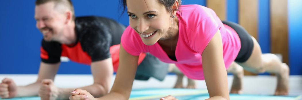 Low angle of smiling man and woman doing exercise for full body, active train in morning. Student repeat after teacher, weekend class. Yoga, hobby concept