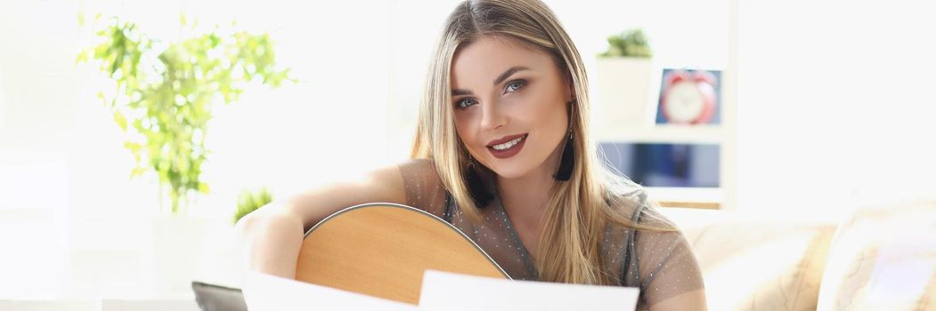 Portrait of pretty woman music composer, blonde with makeup look at camera. Notes on music stand in front. Concert, musical performance, rehearsal concept