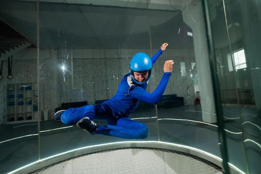 A man in overalls and a protective helmet enjoys flying in a wind tunnel. Free fall simulator.