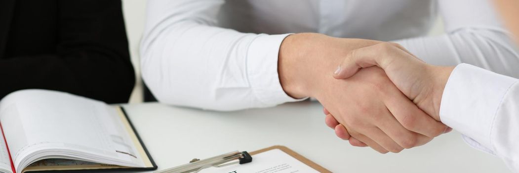 Close-up of partnership agreement between businesspeople, celebrate with handshake. Agreed on business conditions, sign contract paper. Agreement concept