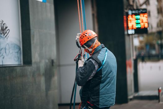 Worker climber preparing for work. Climber tightens the safety belt and check fixing and carbines