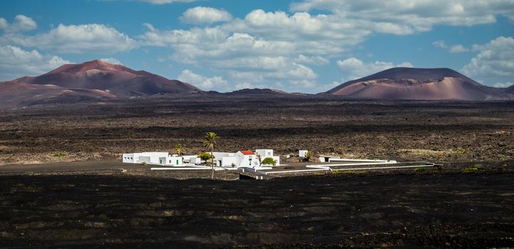 Amazing panoramic landscape of volcano craters in Timanfaya national park. Popular touristic village in La Gueria, Lanzarote island, Canary islans, Spain. Artistic picture.
