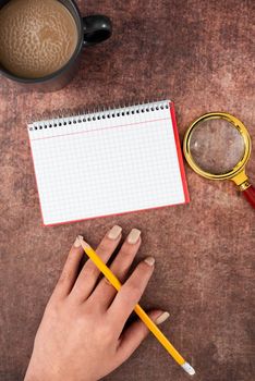 Hand Of Woman Spiral Notebook, Magnifying Glass And Coffee Cup On Wood.