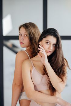 Two young women standing wearing lingerie at home