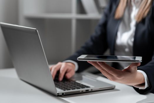 Businesswoman Holding Tablet In One Hand And Typing On Lap Top With Other.