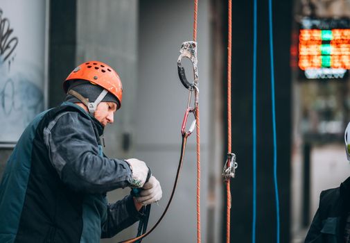 Worker climber preparing for work. Climber tightens the safety belt and check fixing and carbines