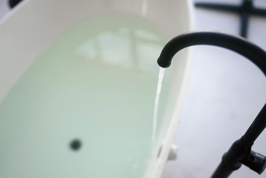 Close-up. water flows from a luxurious water tap into bathtub