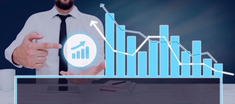 Businessman Pointing On A Chart Showing Crucial Diagrams And Data.