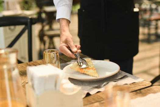 The waiter punishes a piece of cheese on a plate in a restaurant.