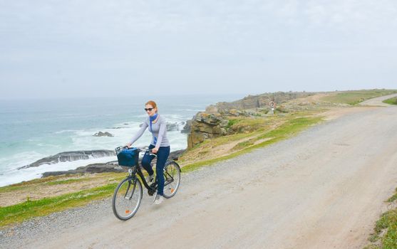 Young lady with bicycle on a sea coast