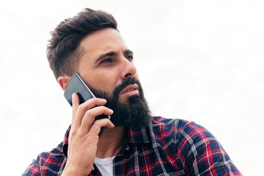 portrait of a handsome bearded man talking by mobile phone, concept of freedom and technology, copy space for text