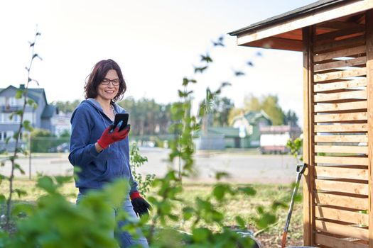 Portrait of a smiley woman using a mobile in a vegetable home garden