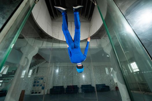 A man in overalls and a protective helmet enjoys flying in a wind tunnel. Free fall simulator.