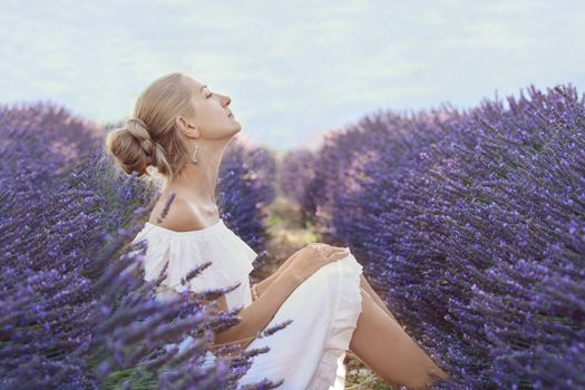 Beautiful woman in a white dress on a lavender field in Provence, France