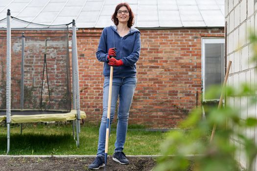 Portrait of a woman with a hoe in a vegetable home garden