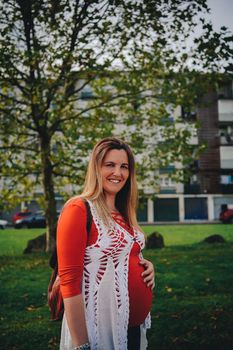 pregnant young woman walking with her hand on her belly