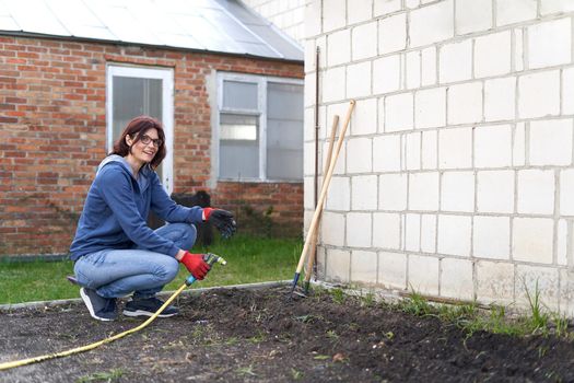 Rural scene of a woman watering seeds on a vegetable home garden