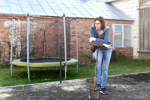 Exhausted woman having a break while working in the land of a vegetable home garden