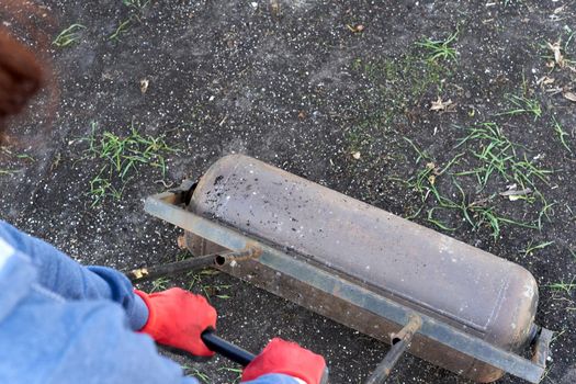 Person flattening the soil in the traditional way using a roller