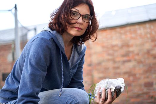 Portrait of a caucasian woman looking at the camera while planting cuttings on the land