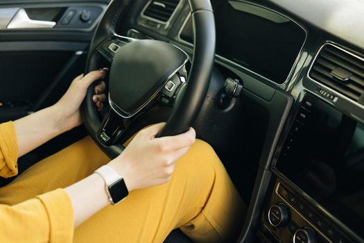 Woman hands holding a steering wheel confidently. Female hands with a clock on the steering wheel of a car while driving.