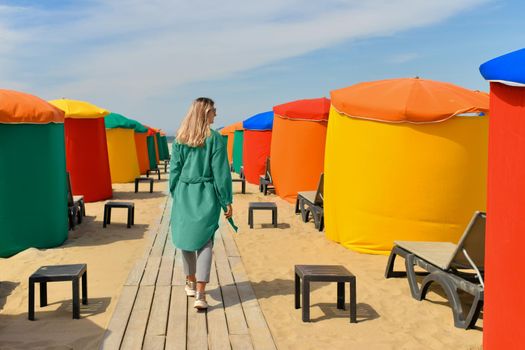 A woman near the typical colored tents and beach chairs