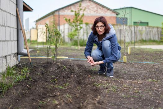 Crouching Woman planting seeds in a vegetable home garden