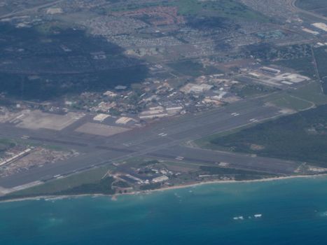 Aerial of Kalaeloa Airport on the coast of Oahu in the state of Hawaii.  Kalaeloa Airport, also called John Rodgers Field and formerly Naval Air Station Barbers Point, is a joint civil-military regional airport of the State of Hawaiʻi established on July 1, 1999 to replace the Ford Island NALF facilities which closed on June 30 of the same year. Located on the site of the developing unincorporated town of Kalaeloa and nestled between the Honolulu communities of ʻEwa Beach, Kapolei and Campbell Industrial Park in West Oʻahu, most flights to Kalaeloa Airport originate from commuter airports on the other Hawaiian islands. While Kalaeloa Airport is primarily a commuter facility used by unscheduled air taxis, general aviation and transient and locally based military aircraft, the airport saw first-ever scheduled airline service begin on July 1, 2014, with Mokulele Airlines operating flights to Kahului Airport on Maui.