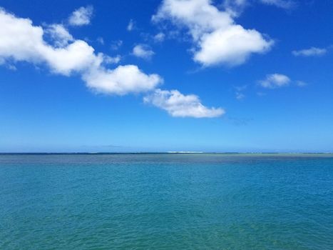 Shallow ocean waters off Maunalua Bay Beach Park looking into the pacific ocean with clouds in the air. 