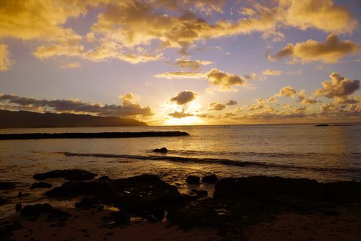 Beautiful Sunset over the ocean with waves moving to rocky shore at Hale'iwa Beach Park on the North Shore of Oahu.    