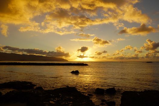 Beautiful Sunset over the ocean along rocky shore at Hale'iwa Beach Park on the North Shore of Oahu.    