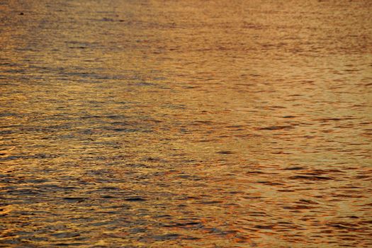 Shades of Yellow-orange Ocean Water ripples off the North Shore of Oahu reflecting dusk light.  Great for backgrounds textures.