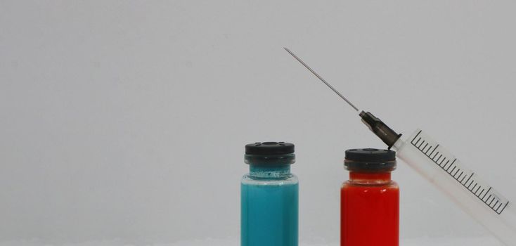 Medical glass vials and a syringe for vaccination. Two ampoules with covid-19 vaccine and a syringe on a white background.