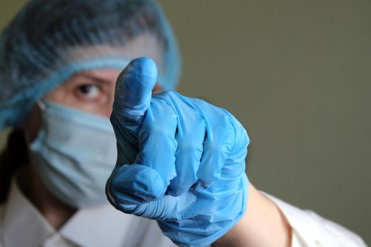 Woman doctor shows index finger in front of her. Hand in a medical glove close-up..