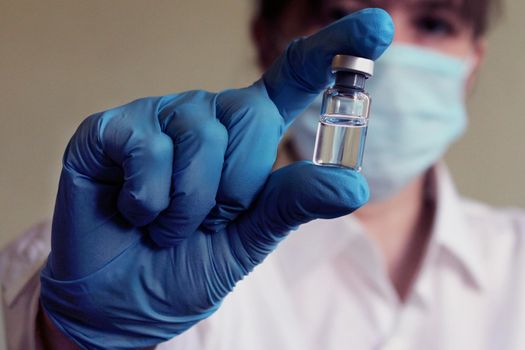 A female doctor holds a vial of vaccine in her hand. Hand close up..