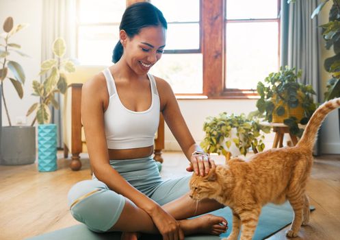 a sporty young woman petting her cat while exercising at home.