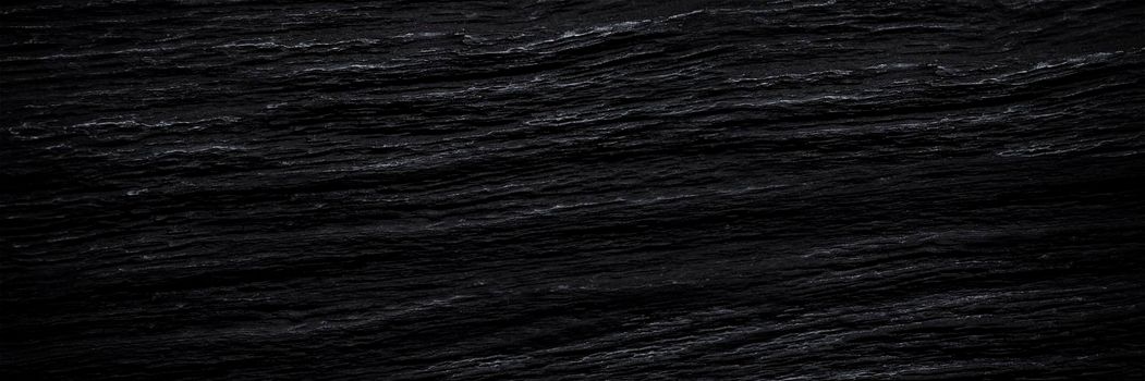 Texture of black old wood. Close-up of the texture of deep black bog oak. Sinuous wood texture with shadow