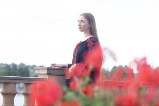 girl in national traditional ukrainian clothes. black and red embroidered dress. woman model posing in park outdoors.