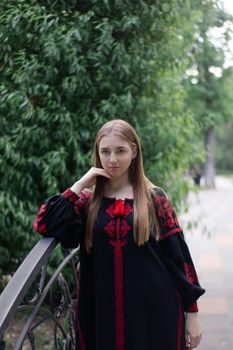 portrait of young woman wearing black and red vyshyvanka. national embroidered Ukrainian shirt. girl in dress outdoors in park. summer.