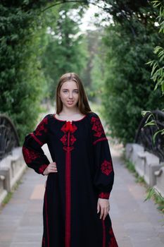 portrait of young woman wearing black and red vyshyvanka. national embroidered Ukrainian shirt. girl in dress outdoors in park. summer.